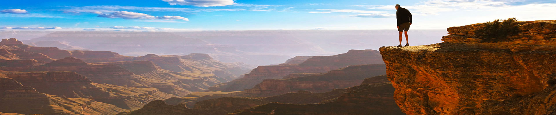 Man looking over the edge of the Grand Canyon while on a hiking tour